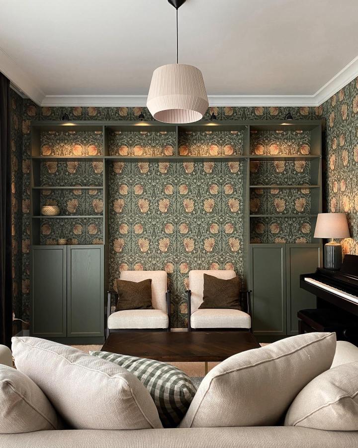 Olive green built-in Billy bookcase in living room with floral wallpaper by @sercemwdomu showing painted ikea billy bookcase ideas.