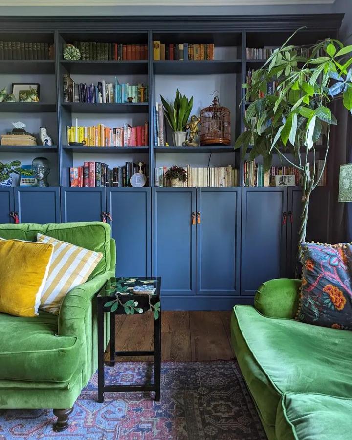 Navy blue painted ikea billy bookcase ideas with leather handles and colorful books styled by @s.e.w.athome in cozy living room.