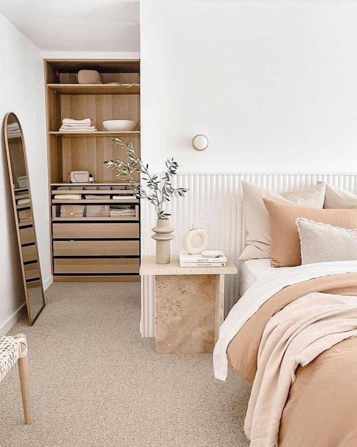Soft beige and cream bedroom with Ikea Pax wardrobe and natural stone side table from @not.another.white.house. Cozy, organized minimalist space.