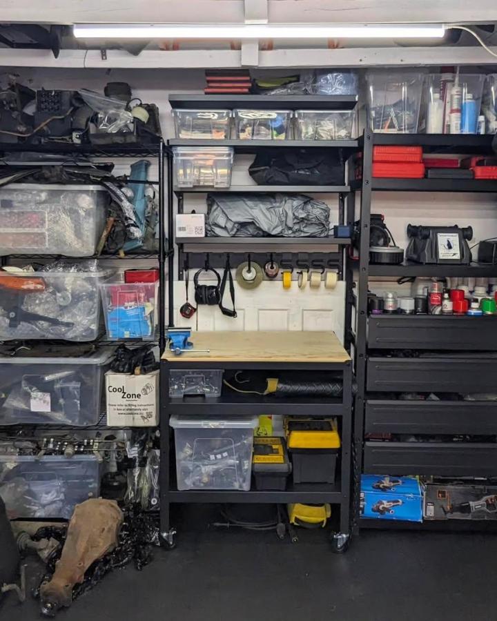 Black metal and wood Ikea BROR shelving workspace from @datsun_fortunate with clear bins and organized tool storage in a garage setting.