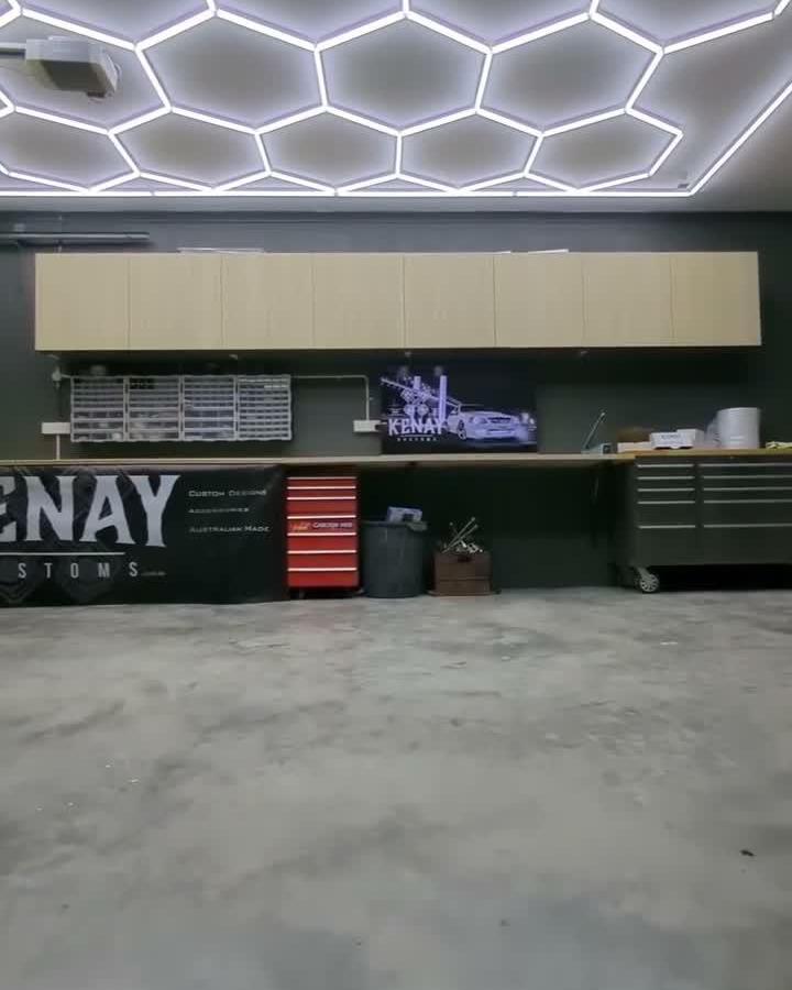 Beige wall-mounted cabinets with tool chests and wire racks in modern garage by @kenaykustoms for organized workspace.