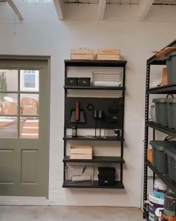 Black wall-mounted metal shelves with wood crates and hanging tools from @no.23_terracehouse showing ikea garage storage ideas in a clean garage.