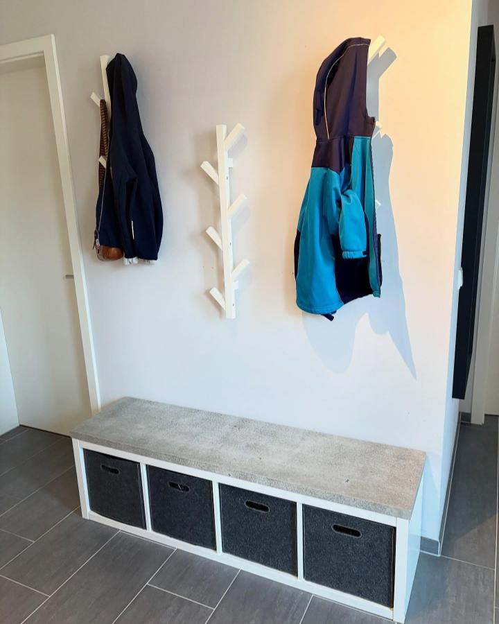 Concrete-look bench with charcoal storage bins and wall hooks by @machbardiy in modern entryway storage setup. Practical and stylish seating solution.