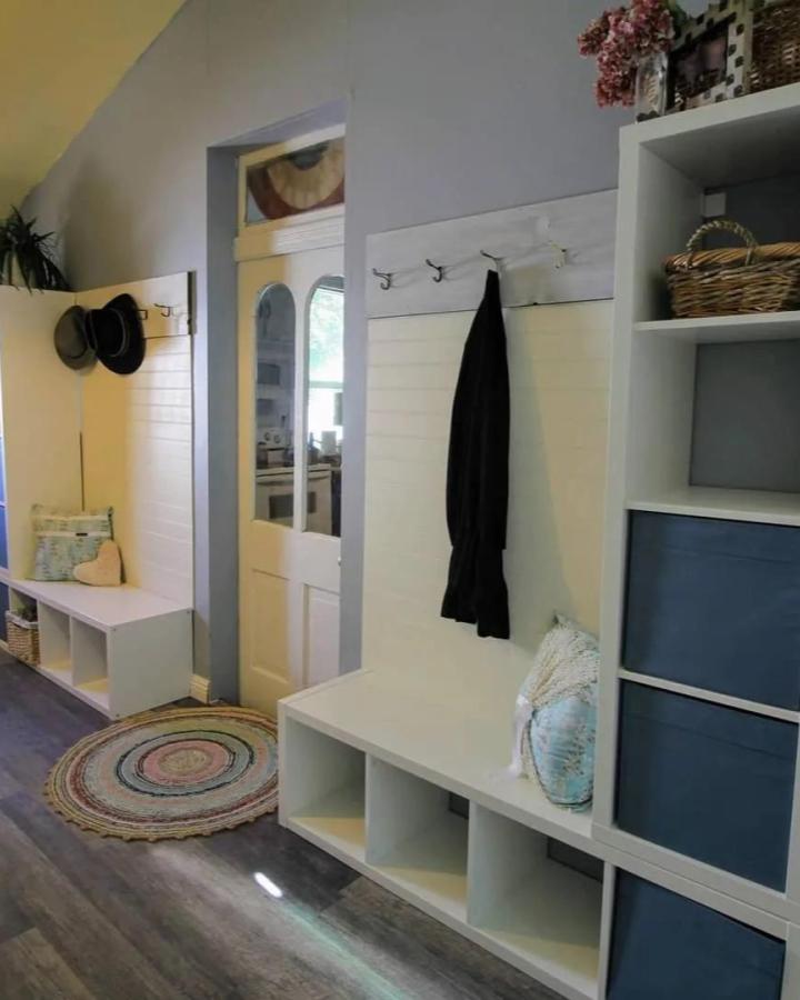 White multifunctional seating and storage unit with hooks and baskets by @maggiesyellowcottage in entryway. Bright and cozy organization idea.