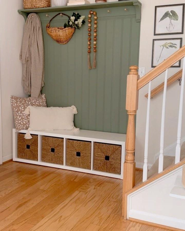 White Kallax storage bench with woven baskets in cozy entry nook by @zulmiv_home featuring natural wood accents and soft green wall paneling.