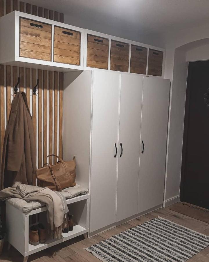 White and natural wood entry storage with black handles from @ilona_wroblewska featuring wooden boxes above white cabinets in a cozy hallway space.