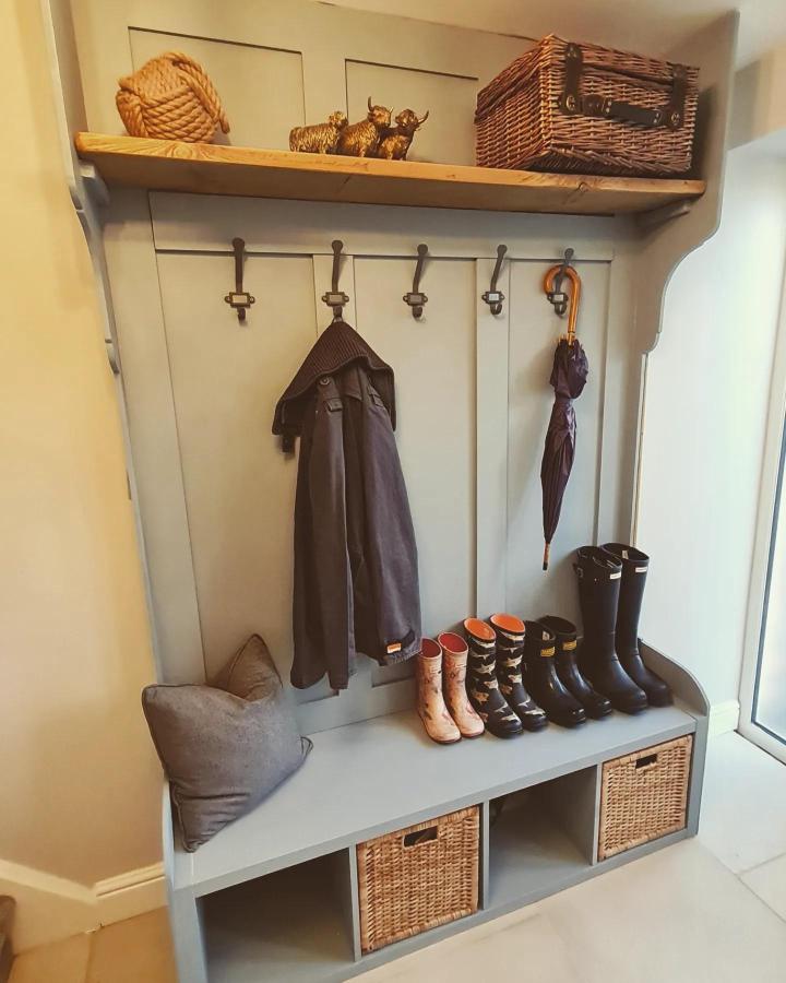 Sage green painted entryway bench with wicker baskets and rustic hooks from @claytonresidence for organized mudroom storage.