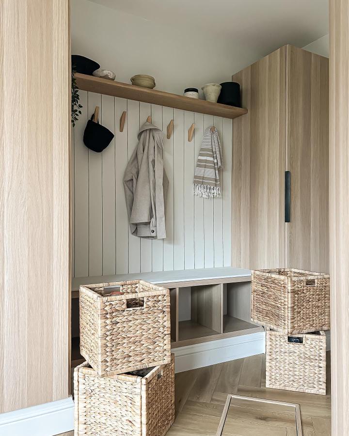 Natural wood Ikea Kallax entryway setup from @klk.interiors with woven baskets and custom bench for ikea kallax entryway hacks.