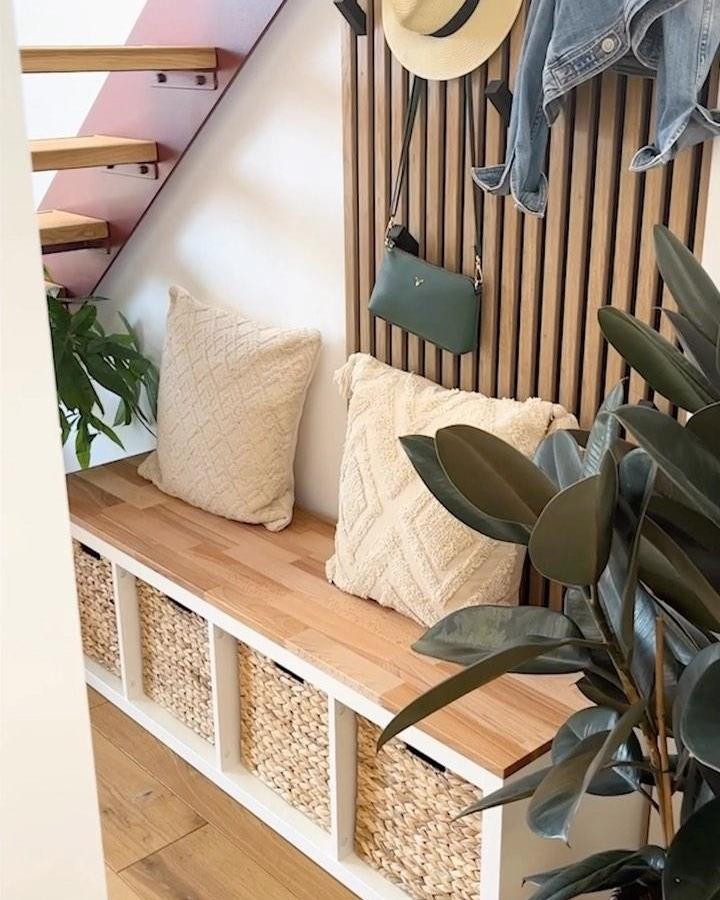 White Kallax bench with natural wood top and wicker baskets entry setup from @trytrytrydiy Featuring cozy pillows and wood slat accent wall for a welcoming foyer space