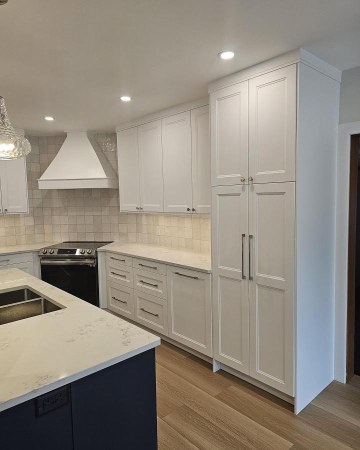 White shaker cabinets and tall pantry storage kitchen by @affordable.kitchen.canada showing elegant ikea kitchen hacks with mixed hardware and soft beige tile backsplash.