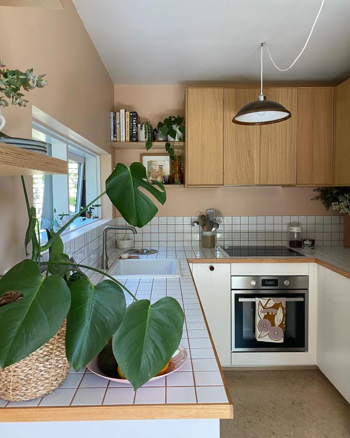 Light oak and white tiled kitchen with plants and custom fronts by @lwdesignandassembly showing creative home kitchen makeover ideas.