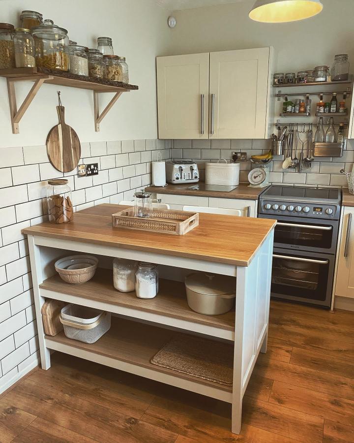 Light wood and white kitchen island with open shelves from @the_one_with_the_green_door featuring smart storage and prep space in a bright kitchen.
