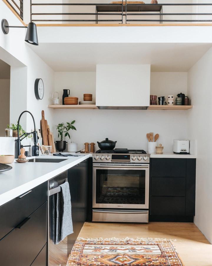 Black custom slab fronts kitchen with natural wood floating shelves from @semihandmade modern contrast and minimalist storage design.