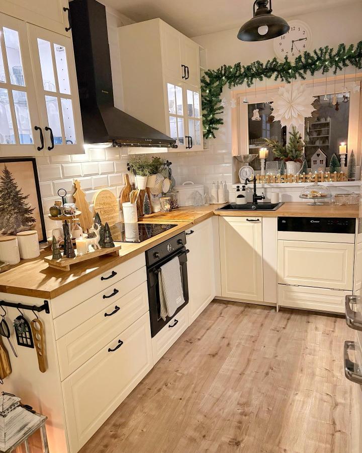 Cream IKEA kitchen with black hardware and wood countertops from @my_kreative_home showing cozy, modern kitchen design with holiday decor and subway tiles.