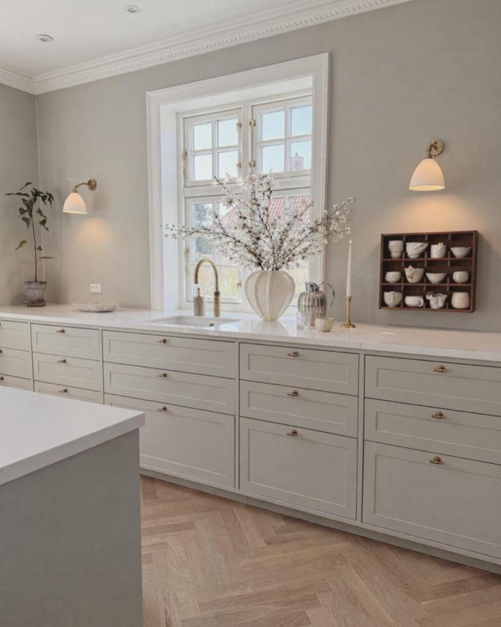 Light gray kitchen cabinets with brass handles and deep drawers by @vores_lille_oase_i_gentofte showcasing refined cabinet upgrades.