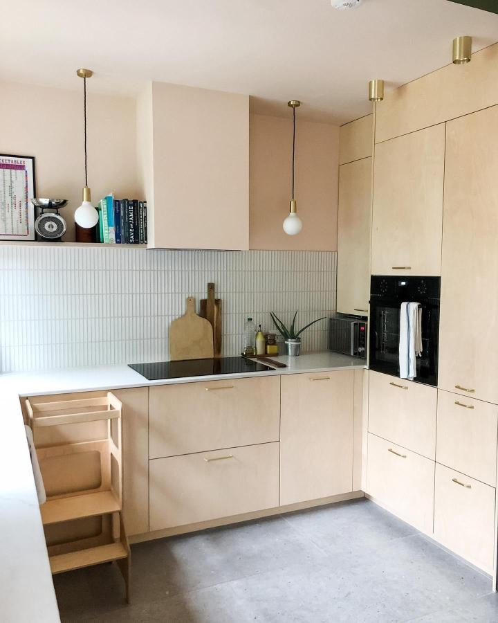 Light plywood kitchen cabinetry with brass handles by @CasaDeMaison showing smart kitchen remodel with custom fronts. Bright and airy space.