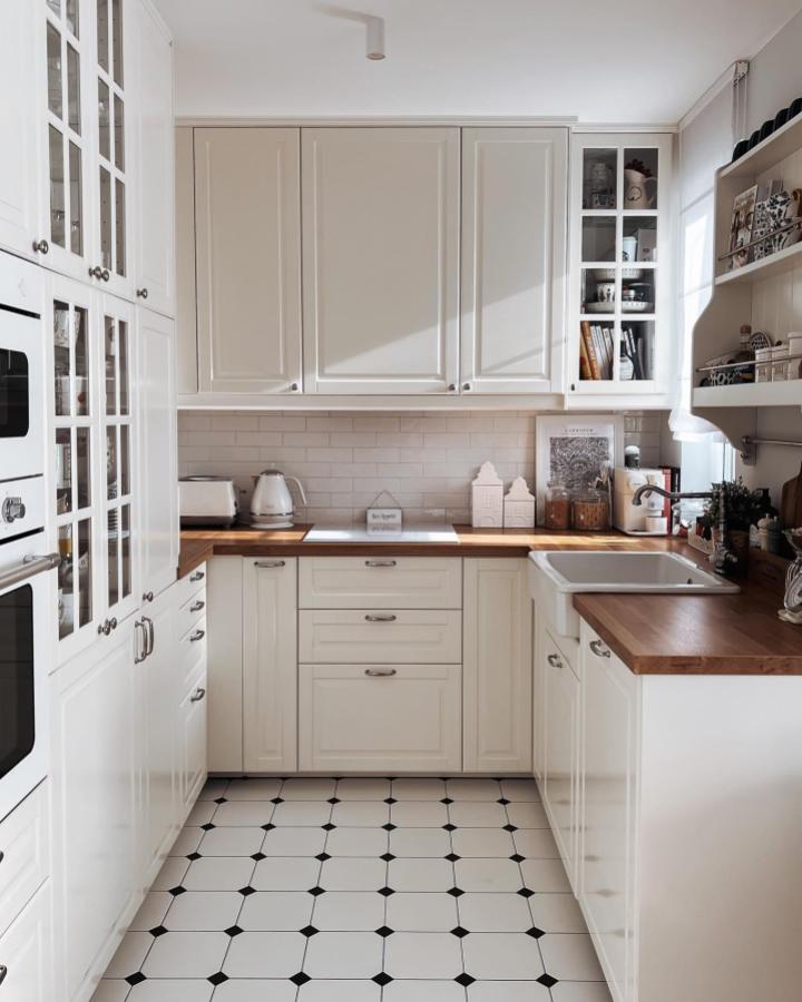 White classic kitchen space with wood countertops and glass-front cabinets by @miskejtpl showing smart small kitchen styling and cabinetry hacks.