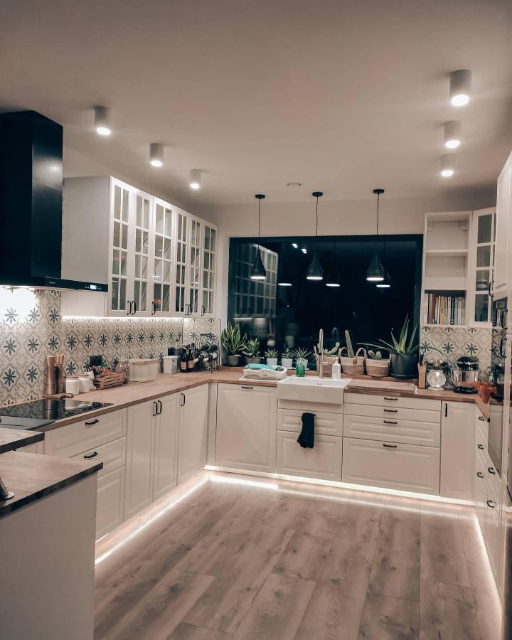 White and wood modern kitchen with LED toe-kick lighting and patterned backsplash by @co.dzis.robimy bright and inviting space.