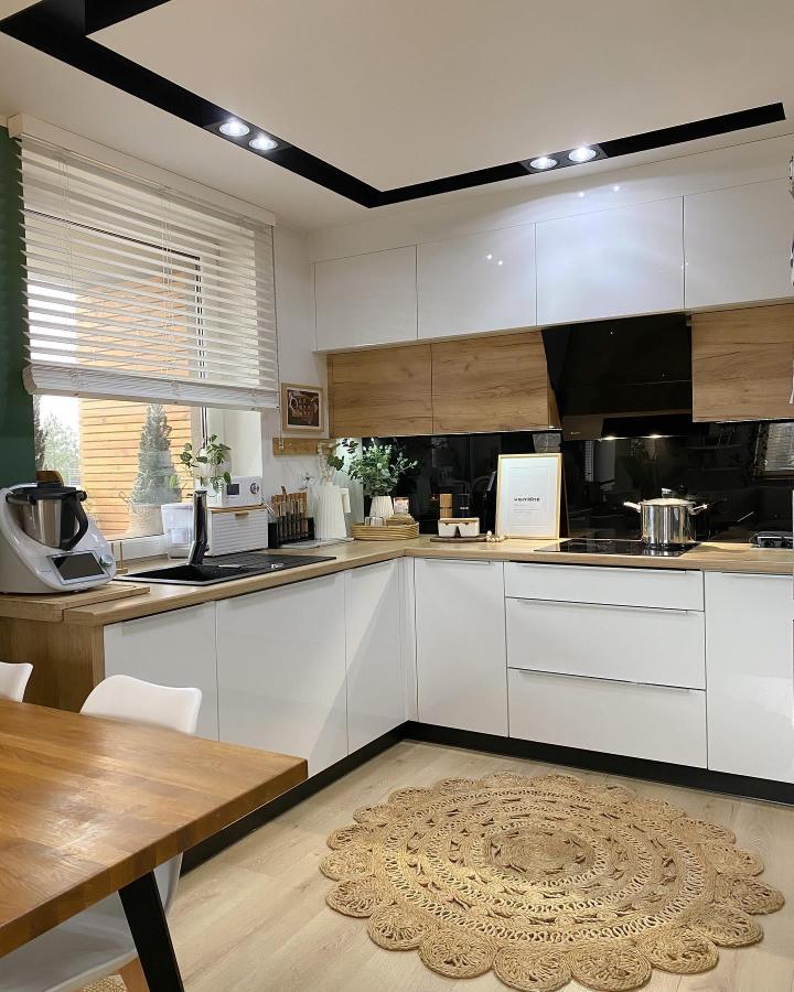 Warm wood accent panels and black backsplash in Ikea kitchen from @my_hygge_my_home showing stylish ikea kitchen hacks with cozy modern design elements.
