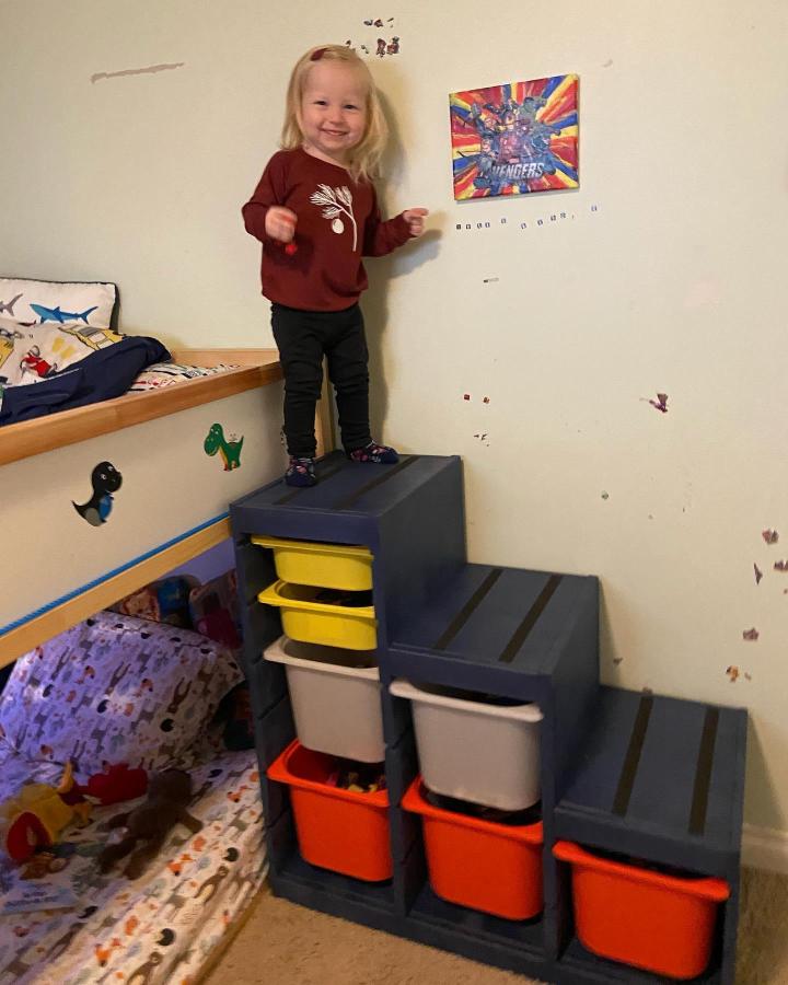 Navy blue stair storage with yellow and orange bins from @rhiannonmaryjones. Functional ikea kura and trofast bed hacks with playful colors and practical design.