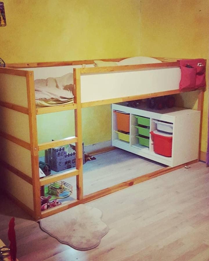 Natural pine wood and white panel Ikea Kura loft bed with colorful Trofast storage bins and pink fabric side pocket from @fanny_ecomum. Organized kids' room solution.