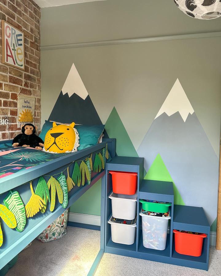 Blue-green painted TROFAST staircase with colorful bins beside IKEA KURA loft bed from @little_edwardian_semi in a mountain-themed kid’s room showcasing ikea kura and trofast bed hacks.