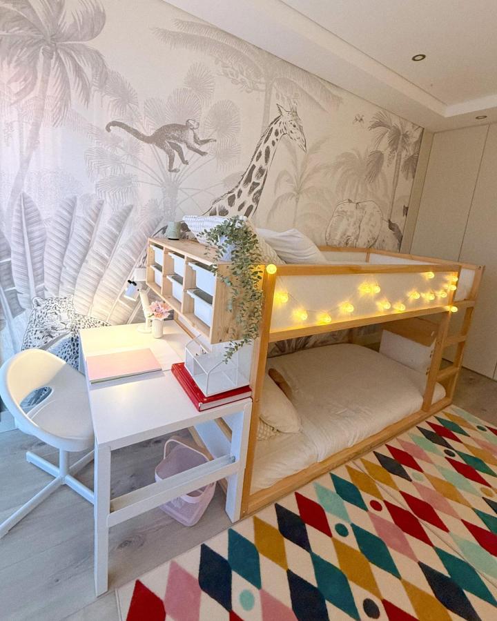 Natural wood IKEA KURA loft bed with TROFAST storage and white desk from @barbara.marques Cozy kids bedroom with fairy lights and jungle wallpaper