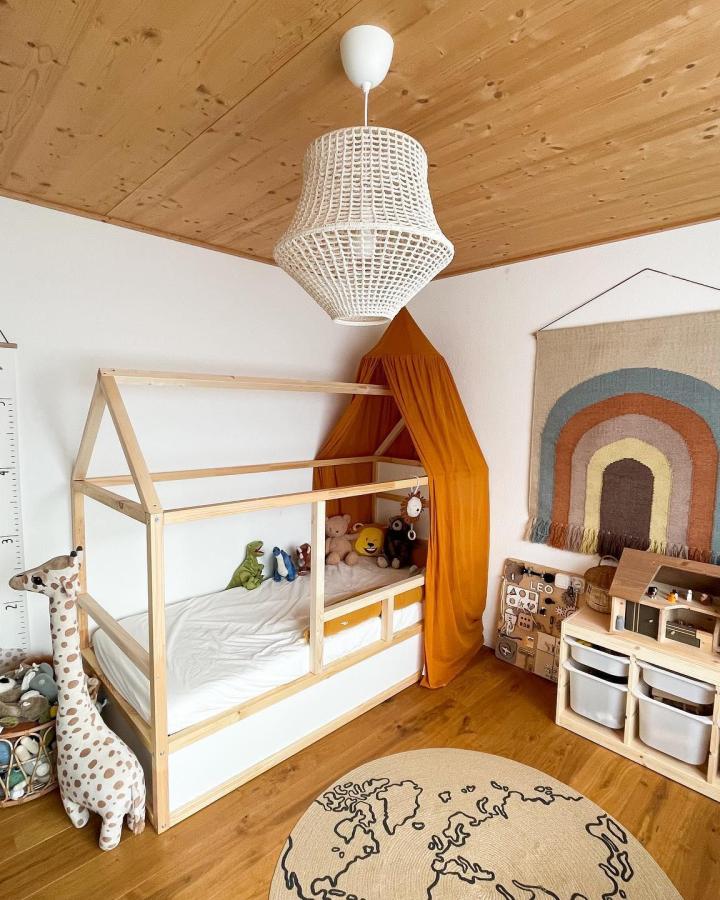 Natural pine house frame bed with burnt orange canopy and white TROFAST storage by @what_petra_loves. Kids room with warm, organized play space.