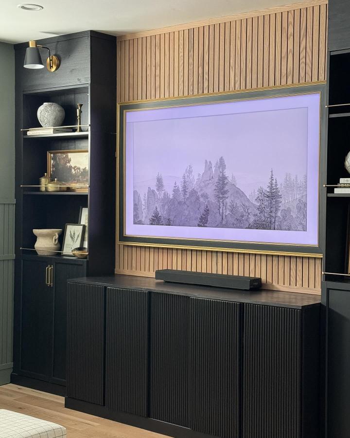 Textured matte black Billy bookcase media wall with natural wood slat paneling from @greybirchdesigns for a modern living room upgrade.