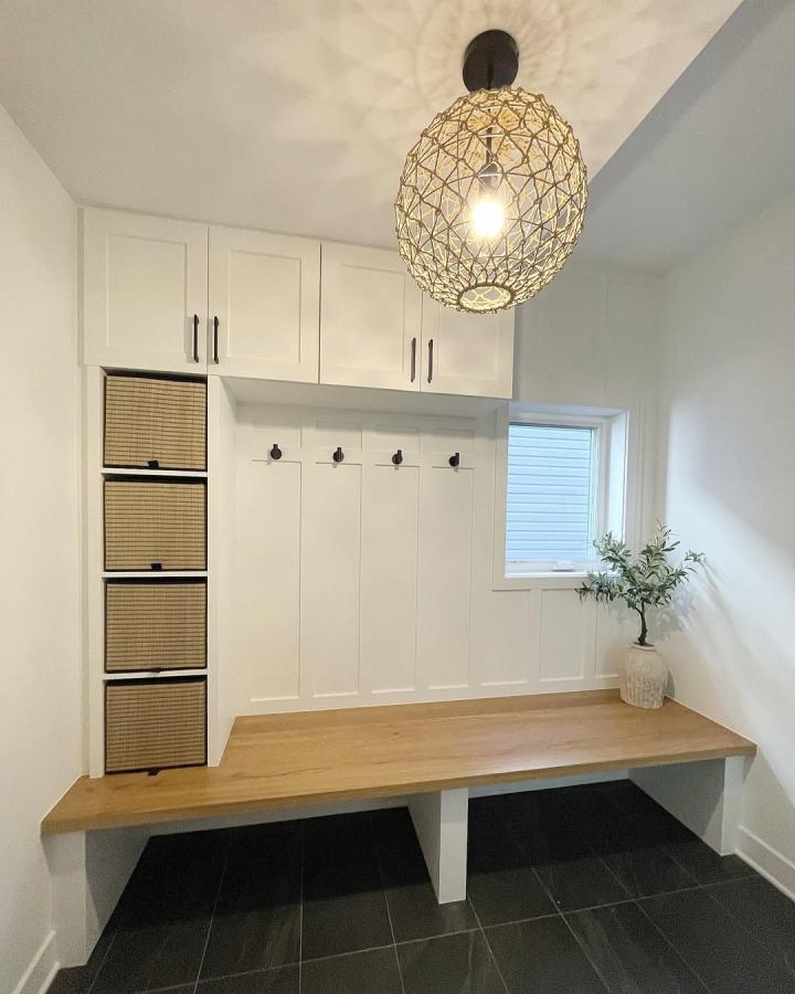 Bright white mudroom lockers with wood bench and woven baskets by @fixitcontracting. Clean, modern organized entry space.