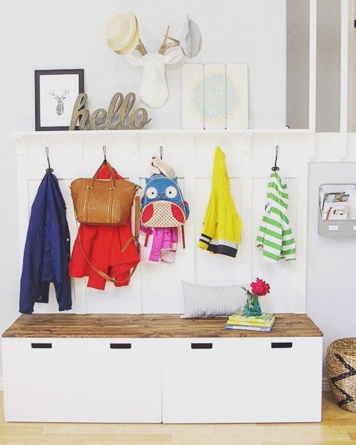 White lockers with wood top and black hooks entryway setup from @themombot with colorful jackets and bags neatly arranged.