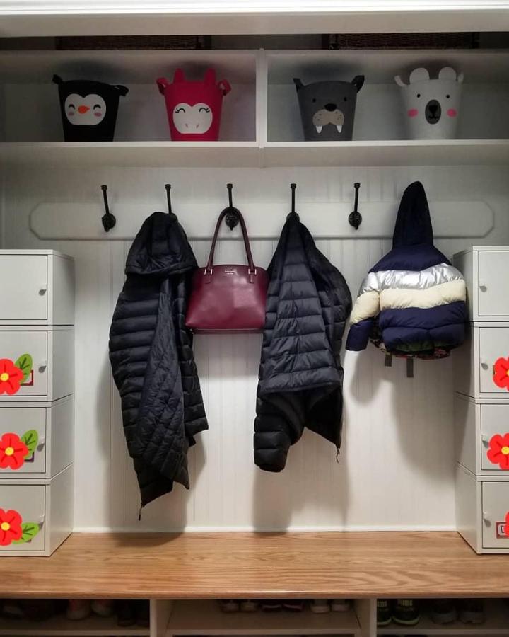 Animal-themed playful storage bins in white mudroom lockers by @hausofbree with hooks and wooden bench for cozy organization.