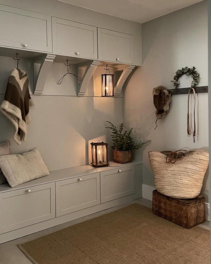 Light gray and wood Ikea mudroom lockers hacks from @homeathand featuring Bestรฅ bench and cabinets with subtle corbels and warm lighting.
