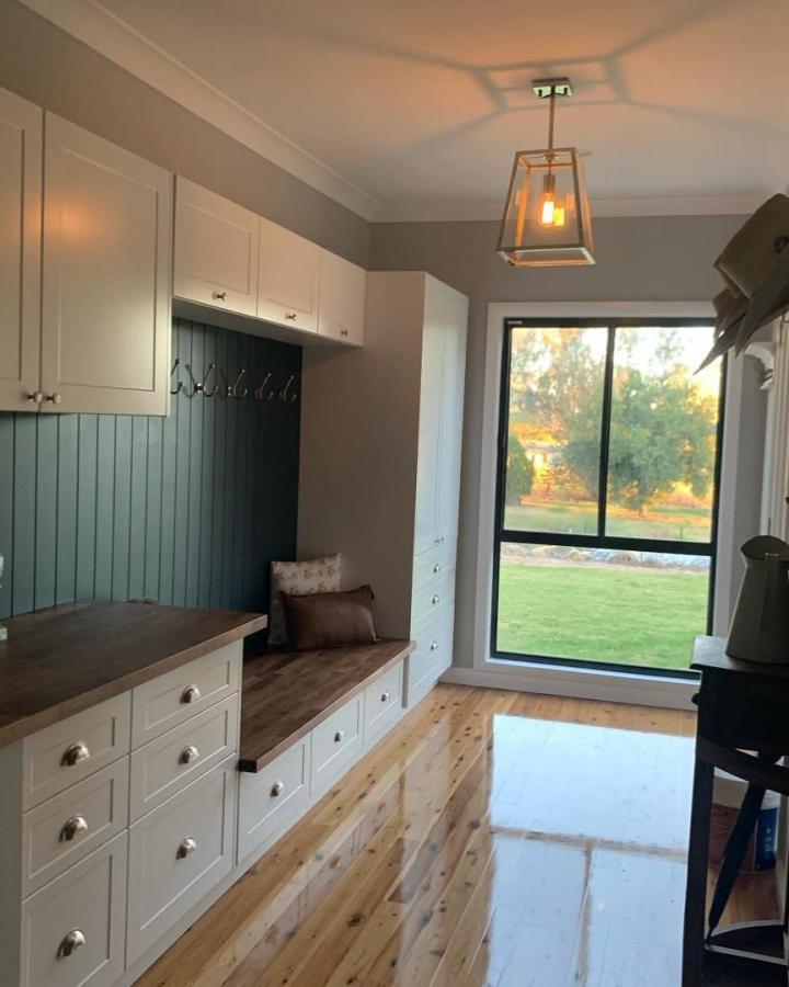 White cabinets and drawers with wood bench and deep blue beadboard wall in mudroom by @lozhanna. Practical and inviting entryway storage.