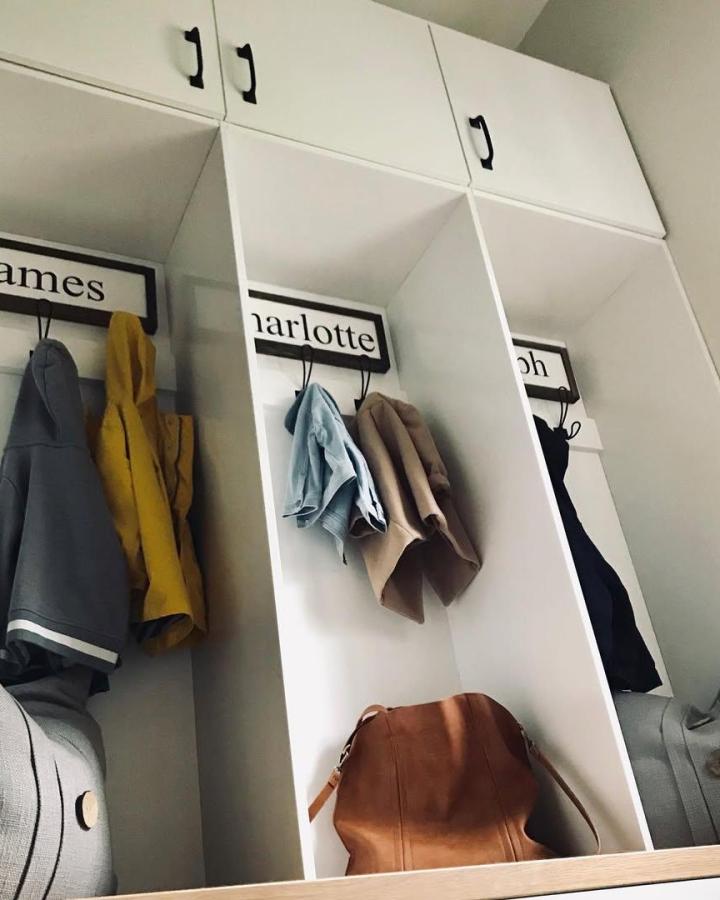 White personalized mudroom lockers from @peardesignstudio made with IKEA Bestรฅ cabinets featuring hooks and black handles.