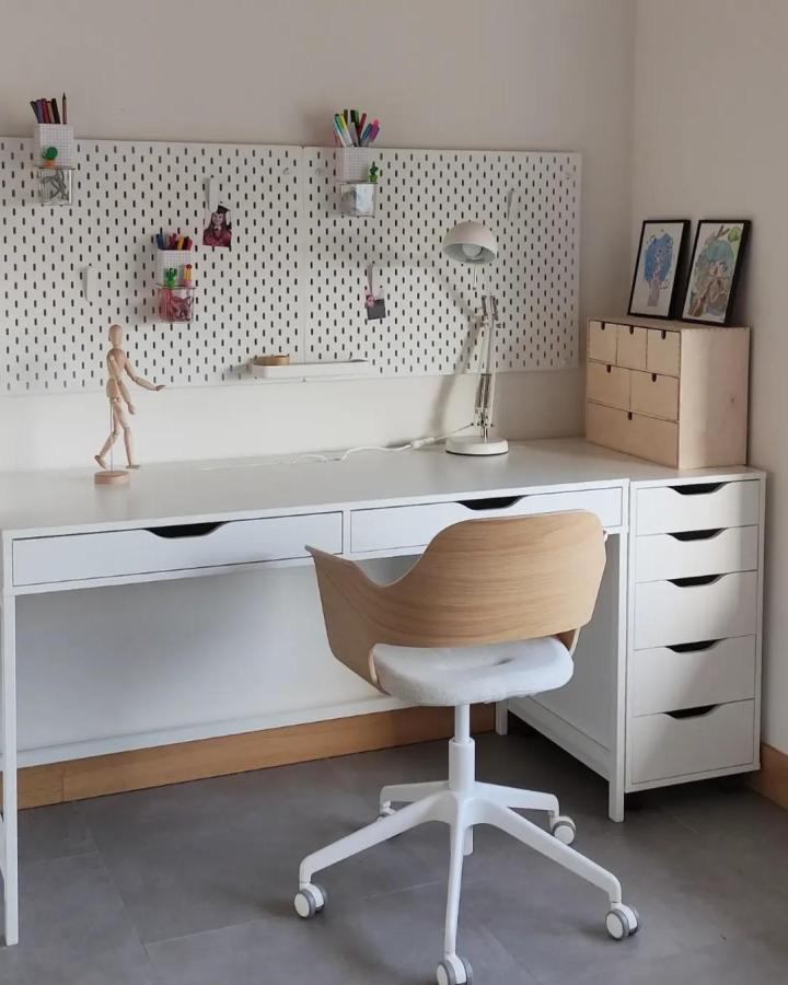 White perforated pegboard panels in office with small containers from @madammemo featuring minimalist design and functional workspace organization.