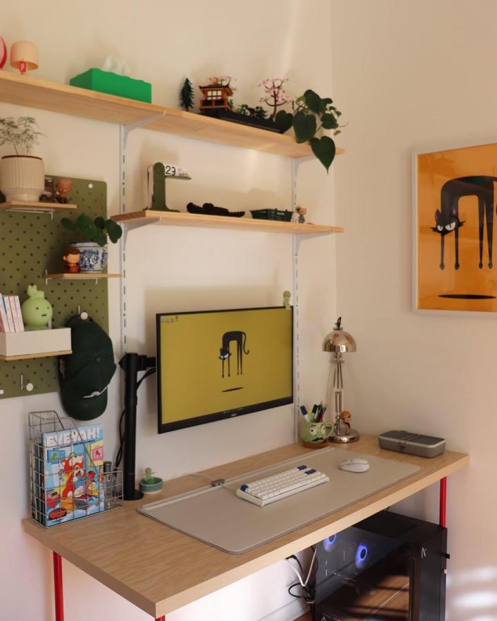 Olive green pegboard wall with wooden shelves and red legs in compact home workspace by @_mochihome, featuring playful decor and smart storage solutions.