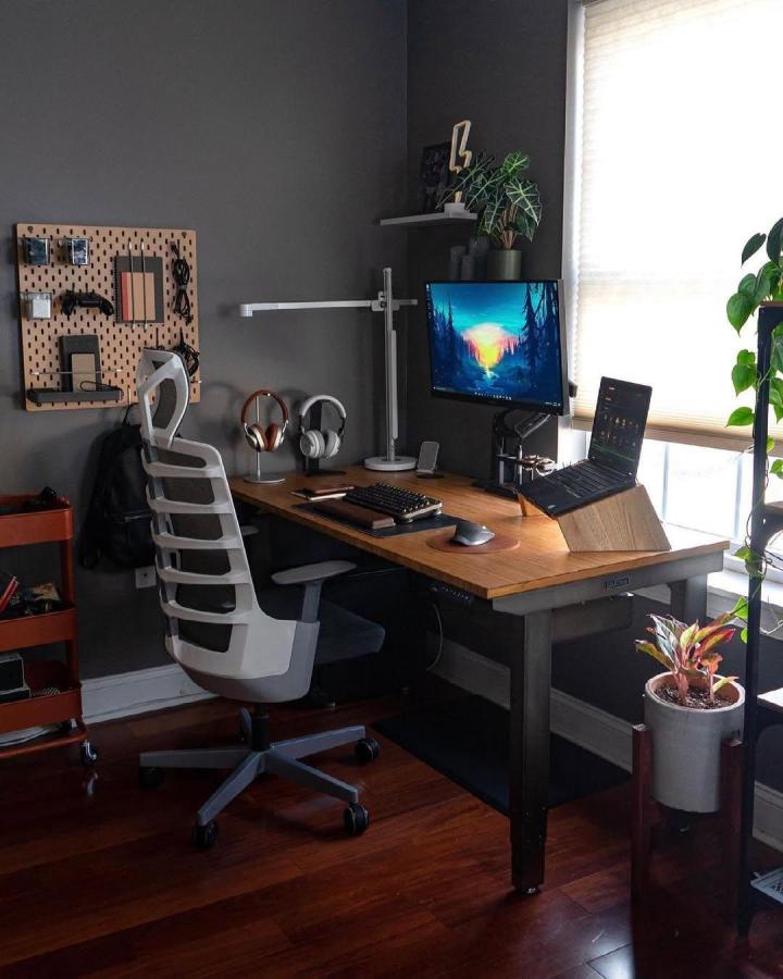 Natural wood pegboard mounted on dark wall in home office by @stylesofman showing ikea office pegboard ideas with organized tech and accessories.