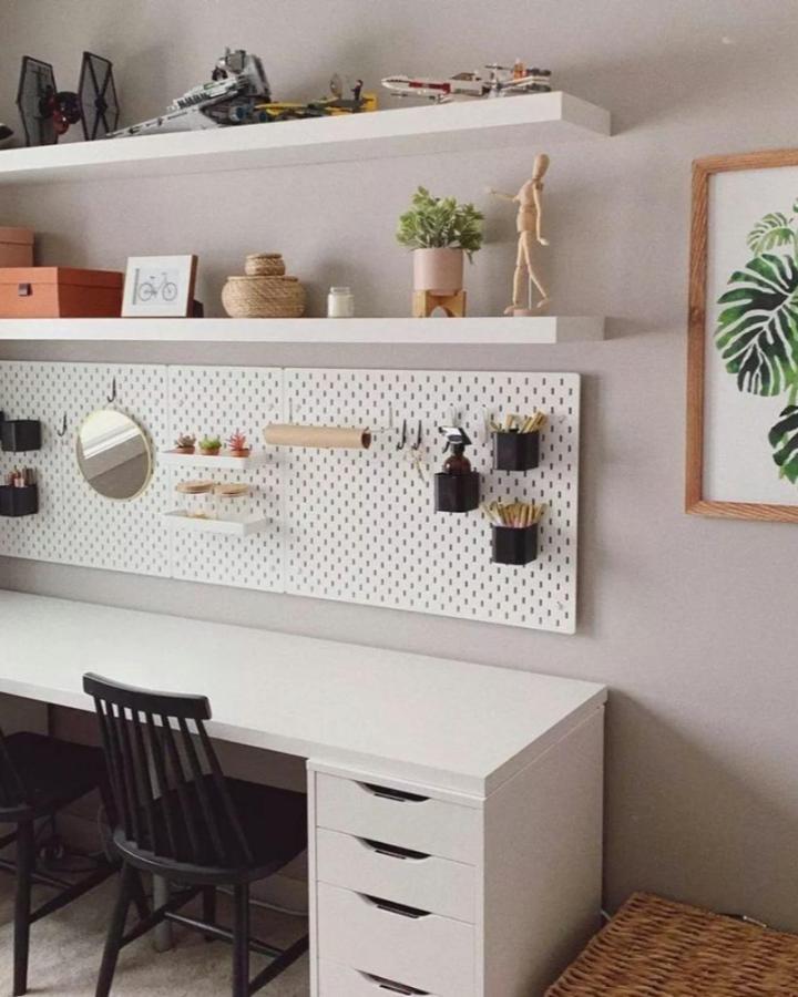 White pegboard with black container hooks and small shelves for an organized office from @_sydneydawn. A stylish example of ikea office pegboard ideas.