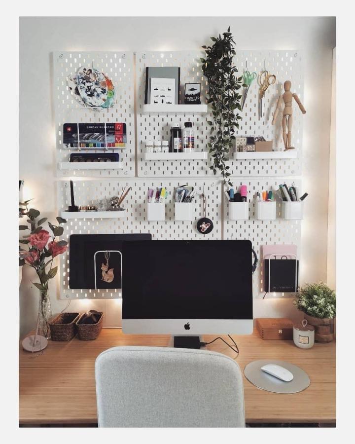 White pegboard with shelves and containers in a tidy home office by @emiliashandmade showcasing ikea office pegboard ideas with greenery and organization.