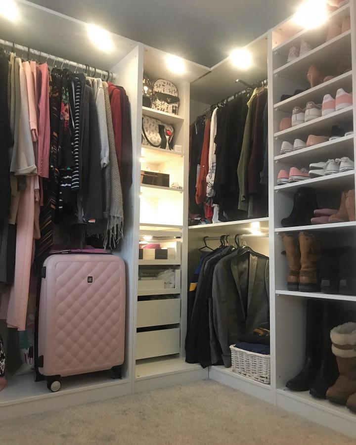 Light-filled white Ikea Pax corner wardrobe ideas from @_oursouterhome__ featuring open shelves, hanging rods, and LED lighting for organized storage.