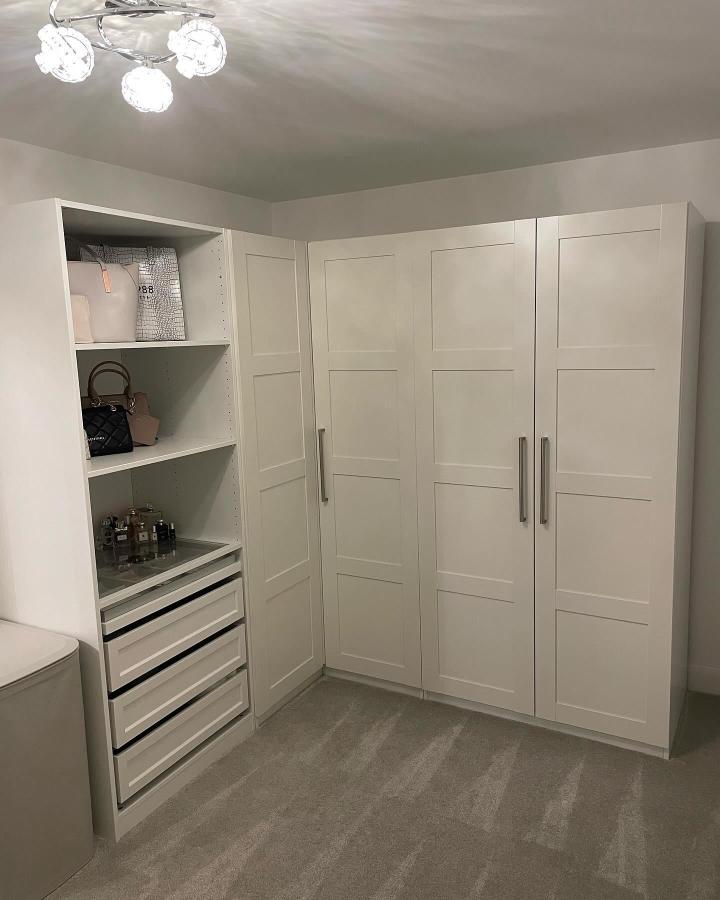 White shaker style corner wardrobe with open shelves and drawers from @ourbovisaspen. Streamlined modern storage with brushed metal handles.