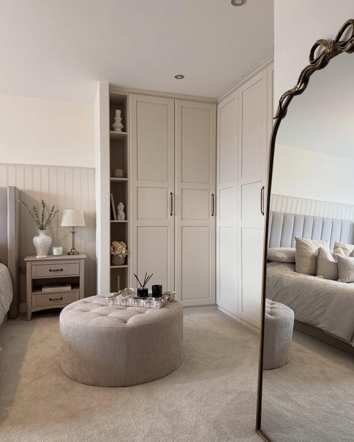 Neutral cream corner wardrobe with open shelving and soft carpet from @lifeatlongtongrange. Stylish bedroom storage solution with calming tones and classic design.