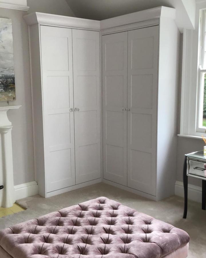 White paneled corner wardrobe with crown molding and subtle beige walls designed by @foxstow blending classic and cozy style
