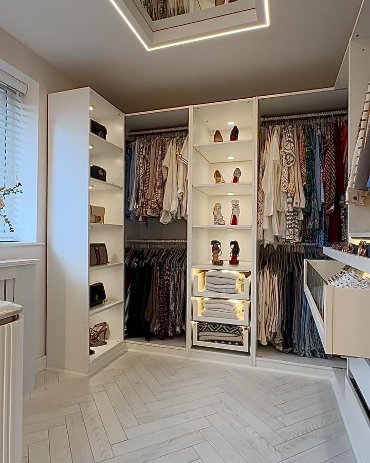 Bright white modern closet shelving with built in lighting from @house_to_home_at_no1 features shoes and clothes neatly organized in a corner room setting.
