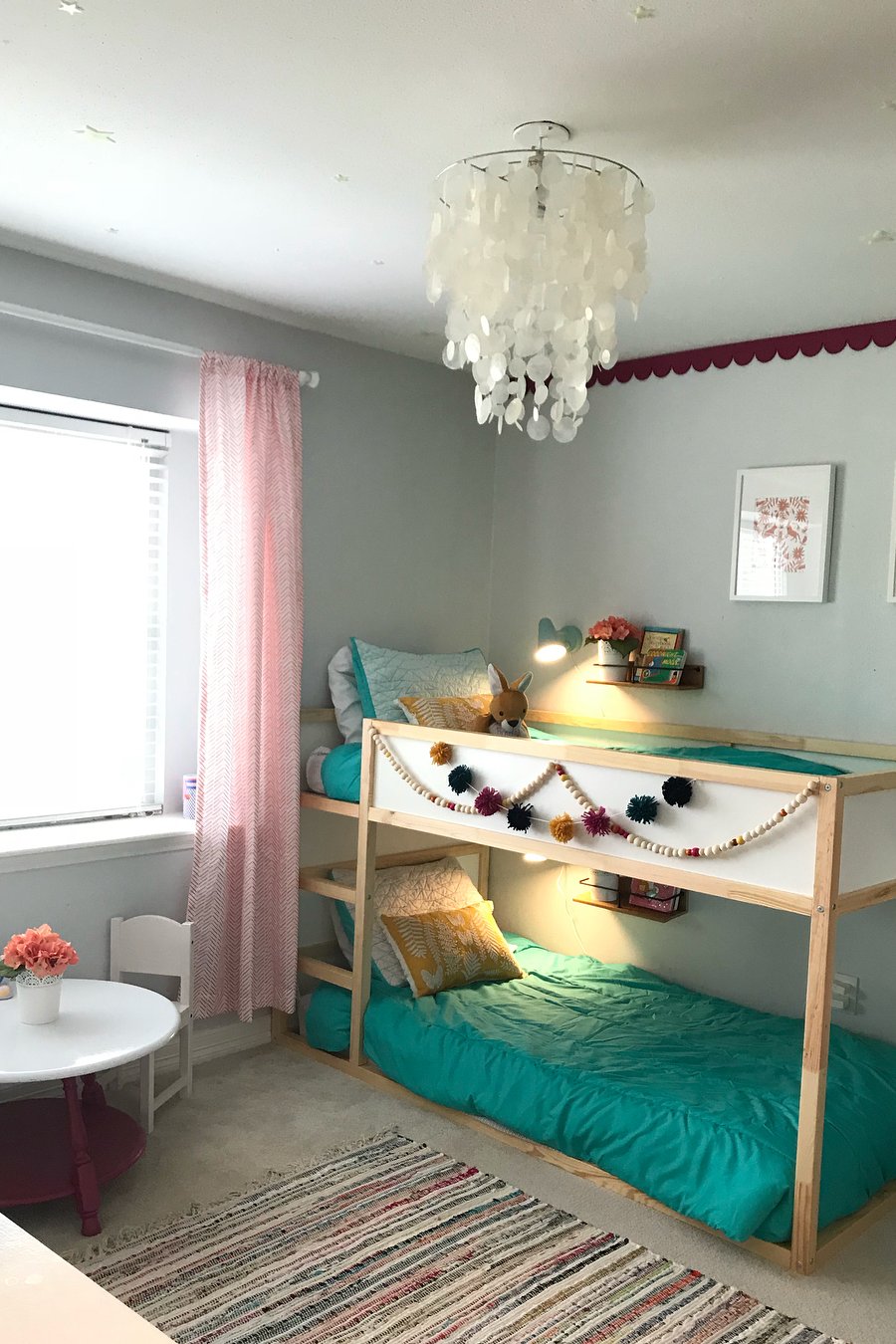 best accessories for ikea kura beds featuring a colorful Pom-pom garland and cozy teal bedding