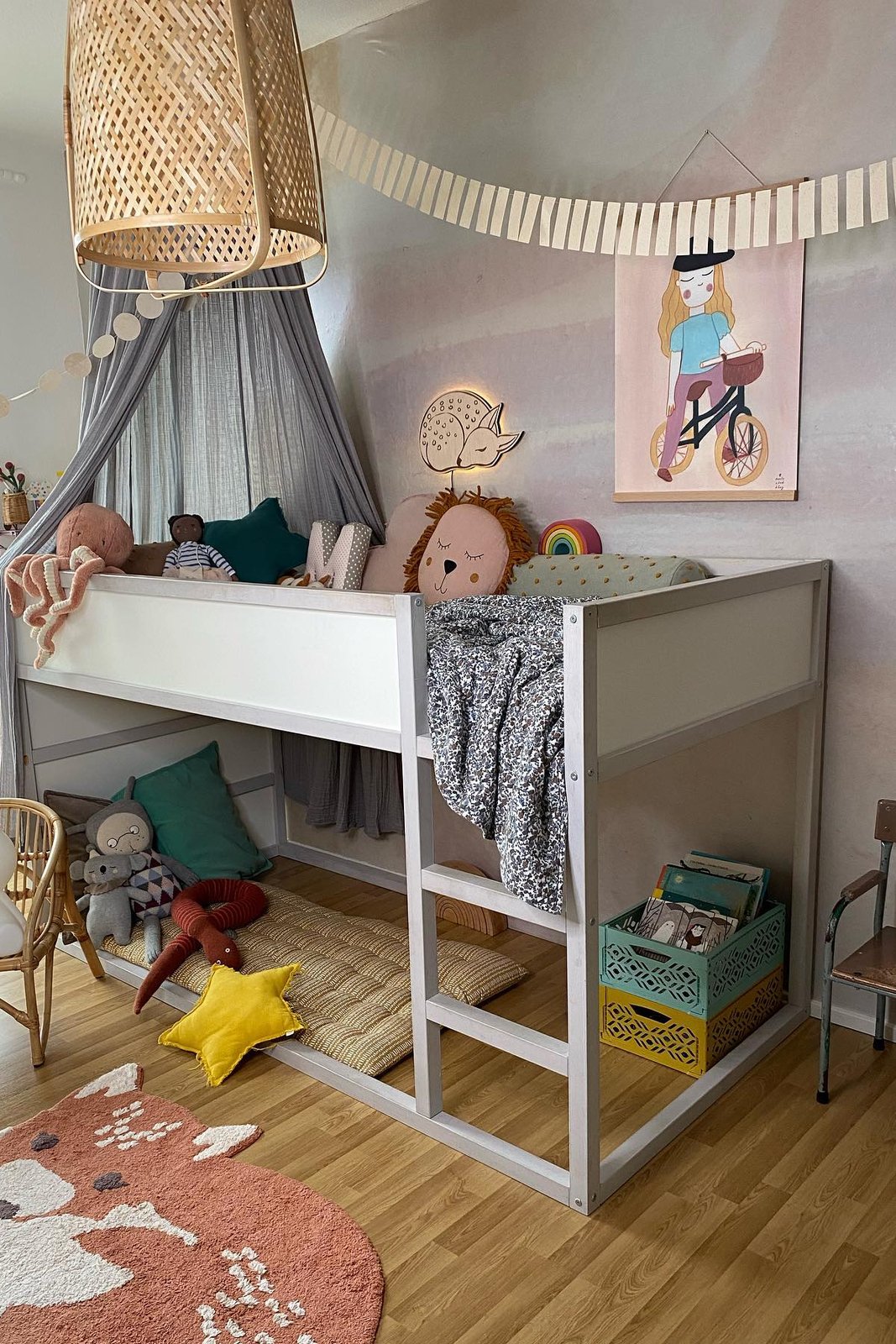 Grey KURA bed with canopy fabric, cushions, garlands, toys, crates, and cozy reading accessories