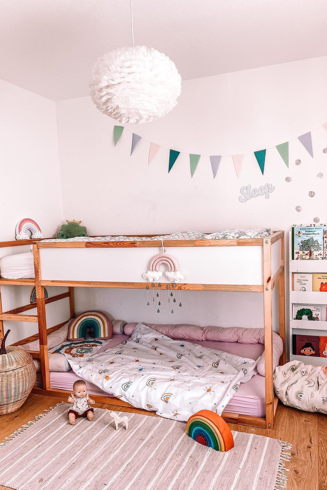 Pastel Ikea Kura bed with rainbow mobile, bunting, cozy bedding, and playful nursery accessories