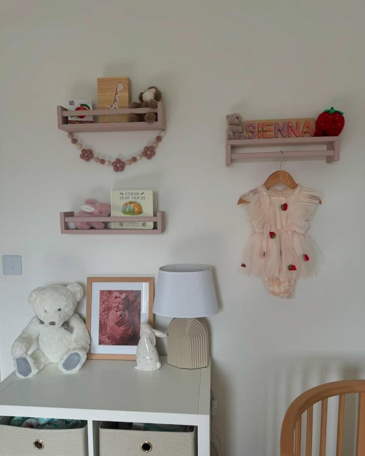 Soft pink painted wooden nursery shelves from @sarahxhome holding toys and books with a cozy modern touch.