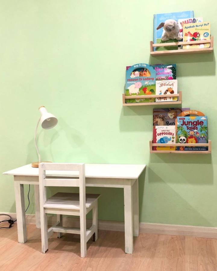 White ikea bekvam desk with natural wood floating shelves by @lebok_kamei in nursery corner featuring kids books and soft green walls ikea bekvam nursery ideas.